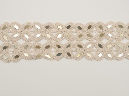 Galon ajouré au crochet en pur coton coloris écru tombé de métier de 80 mm de largeur, orné de motifs floraux géométriques brodés de paillettes navettes métallisées pour la confection vestimentaire, la customisation et la décoration textile.